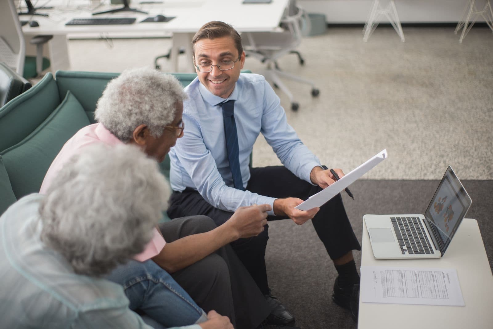 A licensed credit counselor reviewing a plan with an older couple in a warm office.