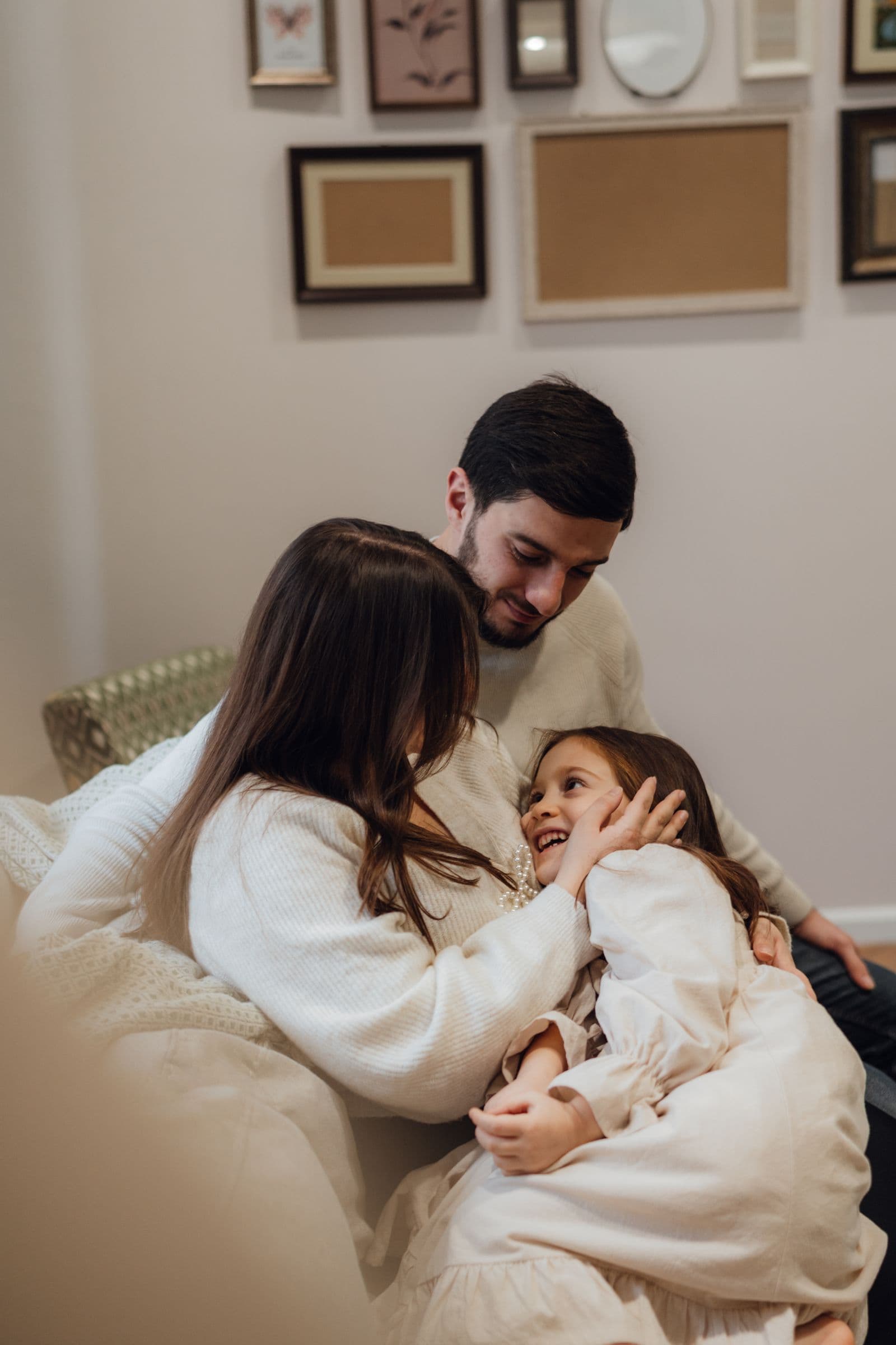 Parents embracing their smiling child at home.