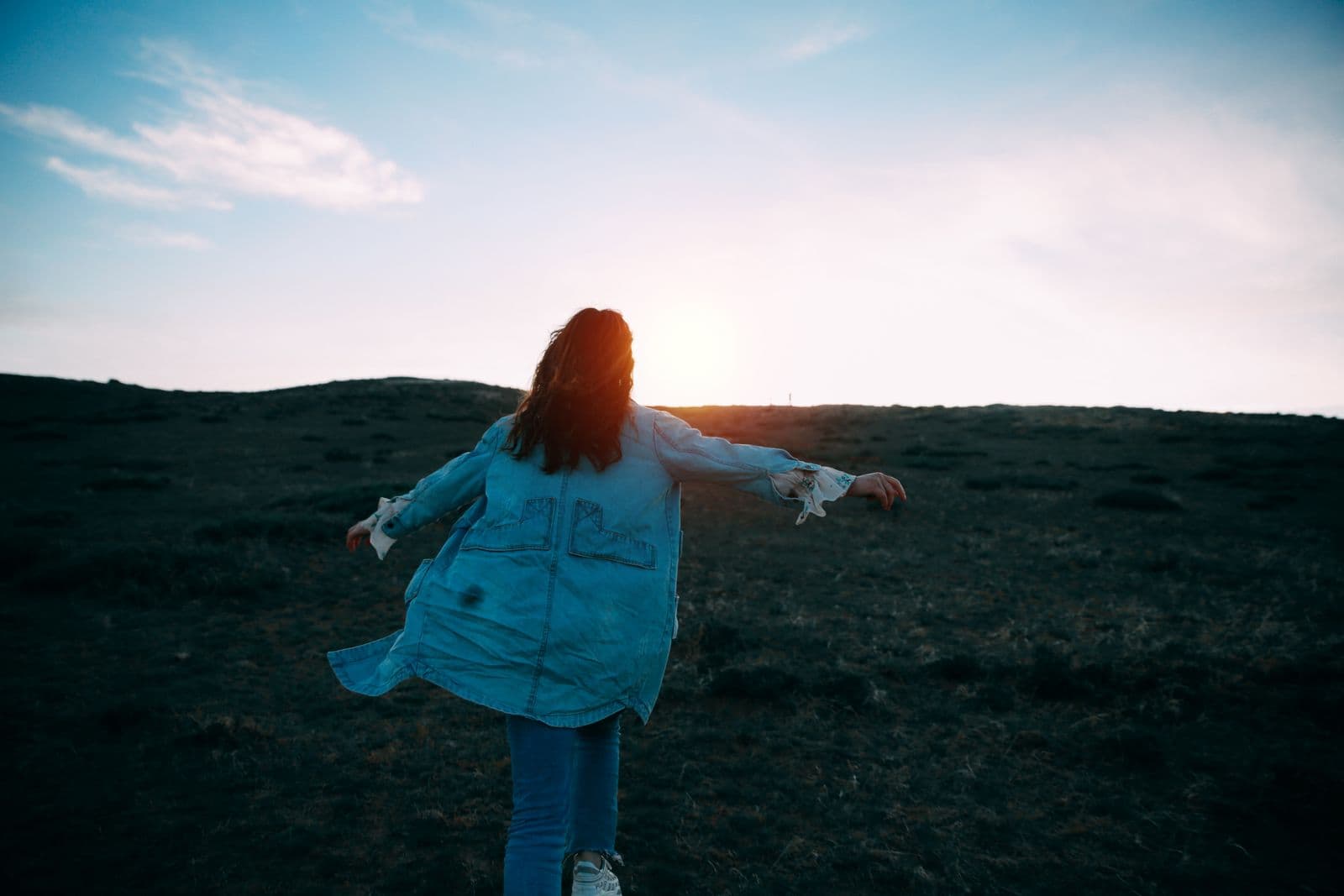 A woman in an open field at golden hour, relaxed and free.